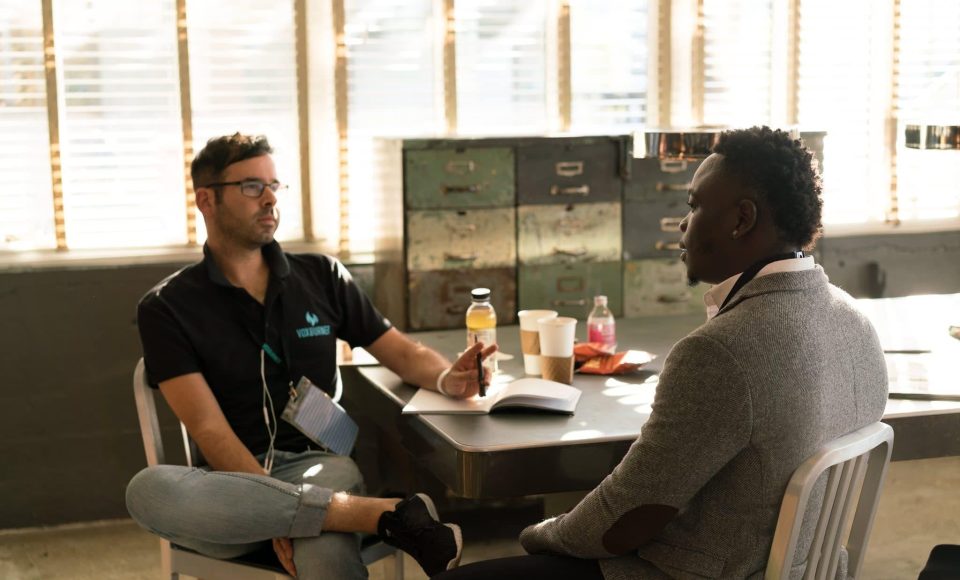 man-wearing-black-polo-shirt-and-gray-pants-sitting-on-white-935977